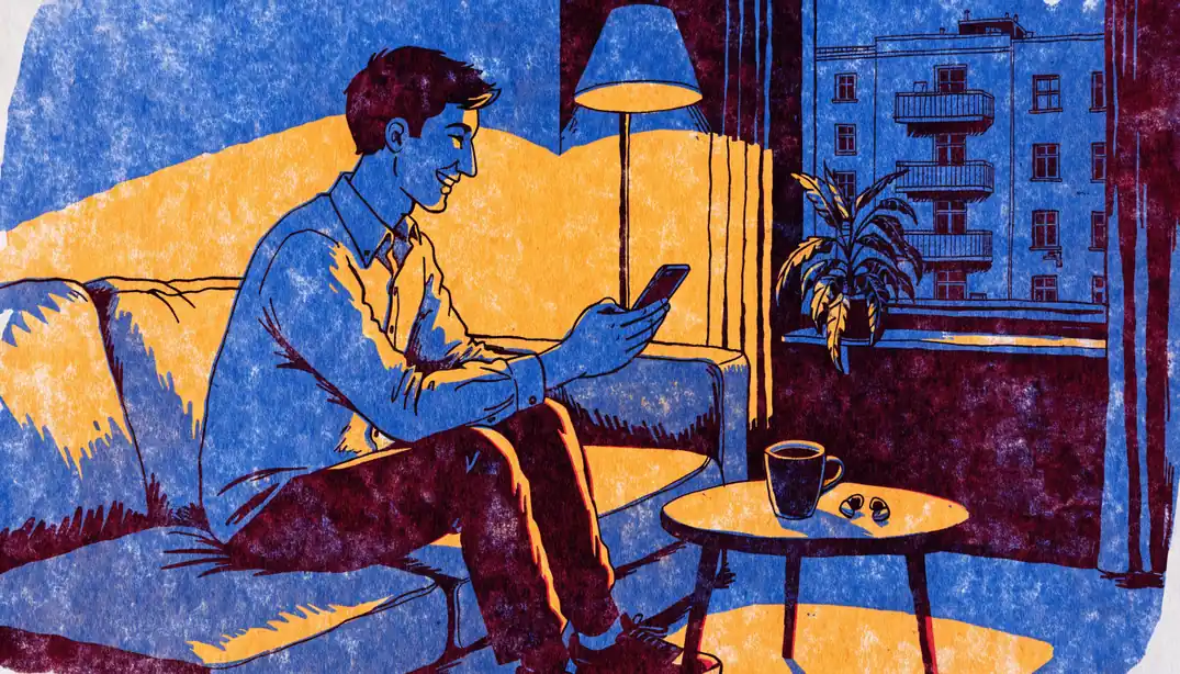 Junger Mann entspannt abends mit Smartphone auf der Couch in einer modernen Berliner Wohnung.